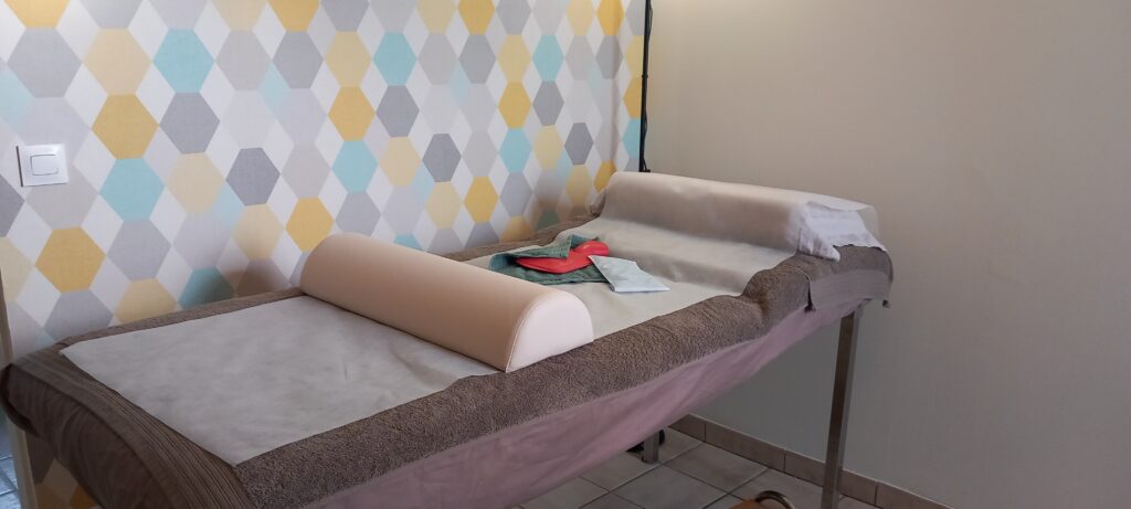 Table de massage équipée pour une séance de dérivation des toxines avec bouillotte chaude et poche froide, prêt pour une thérapie thermodifférentielle.